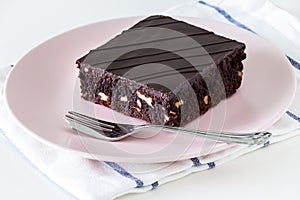 Dark chocolate vegan brownie cake with nuts pink plate.