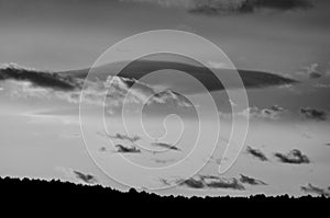 Dark cloud resembles a space ship appearing behind low floating small clouds on an autumn evening Jenningsville Pennsylvania