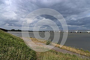 Dark clouds above Hollands Diep water with train bridges over it named Moerdijkbruggen photo