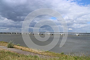 Dark clouds above Hollands Diep water with train bridges over it named Moerdijkbruggen photo