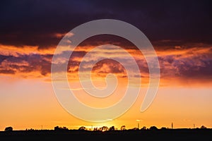 Dark clouds above orange sunset sky