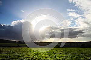 Dark clouds and sun on grass field