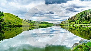 Dark Clouds and surrounding Mountains reflecting on the smooth water surface of Trapp Lake