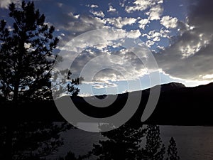 Dark clouds threaten rain over a lake and valley of pine