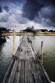 Dark clouds at wooden jetty. sandy beach on the horizon and mosque