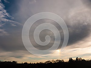 Dark cloudy moody sky over tree line silhouette background lands