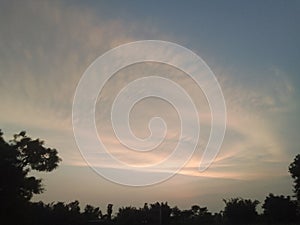 a dark and cloudy sky over a town with trees at sunset