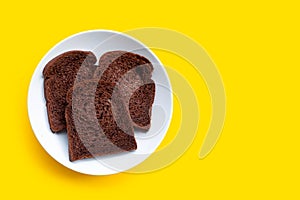 Dark cocoa bread in white plate on yellow