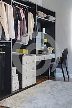 Dark color scheme modern walk in closet design with black chair