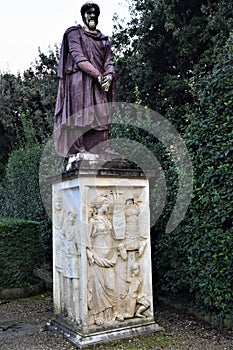 Dark colored statue depicting a man, on an important white stone pedestal enriched by bas-reliefs, in the internal courtyard of Pa