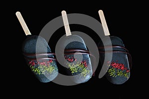 Dark colorful ice cream gelato popsicles glazed with dark chocolate isolated on black background