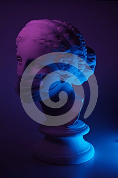 Dark and conceptual image of a female bust in greek style with mask
