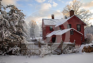 Dark coral painted 18th century New England clapboard home on snowy day at dawn