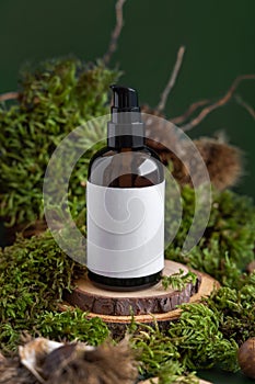 Dark Cosmetic bottle with blank label on wooden piece between green moss, close up, mockup