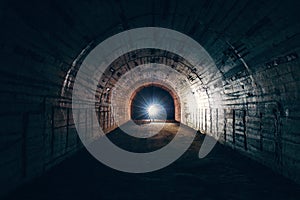 Dark creepy abandoned underground tunnel or vault corridor in bomb shelter and man with flashlight, abstract light in end concept