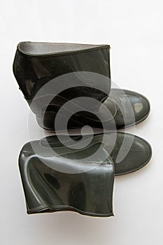 Dark crumpled rubber boots stand, isolated forn, close-up