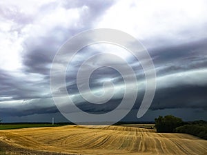 Dark cumulonimbus clouds bringing heavy rain over harvested agrarian fields photo