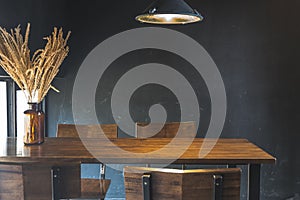 Dark dining table with wooden chair and dry flower