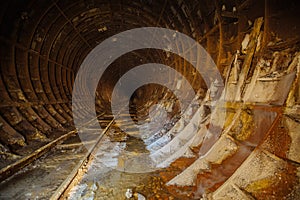 Dark dirty abandoned subway tunnel with rusty railway