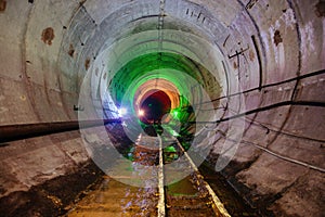 Dark dirty abandoned subway tunnel with rusty railway