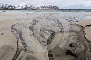 Dark drawings on a beach made by  stream near Flakstad at Lofoten islands in Norway.