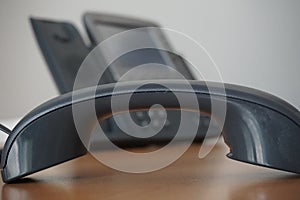 Dark earphone (receiver) with a corporate business landline telephone in the background