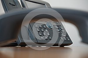 Dark earphone (receiver) with a corporate business landline telephone in the background