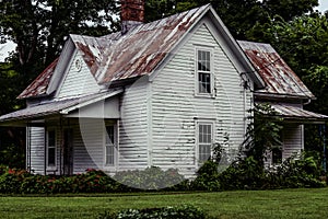 Dark, eerie old abandoned farmhouse with patina roof