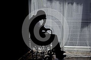 Dark emotion of handicapped Man sitting on wheelchair in front of a large panoramic window in hospital,He is sad and lonely