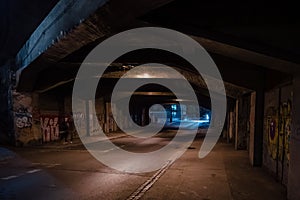 Dark empty dirty grunge underground concrete tunel with a road during mystic night with blue street