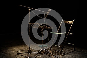 Dark empty room with a microphone and a chair on a stage
