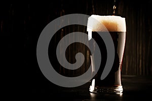 Dark english beer, ale or stout is poured into glass, dark bar c