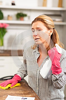 Dark-eyed mature woman feeling really sick cleaning apartment