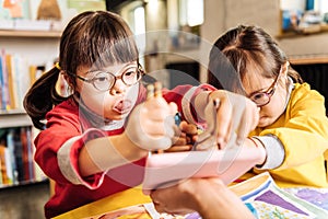 Dark-eyed sunny child playing with her groupmate in kindergarten