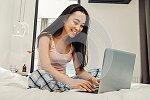 Dark-eyed woman having video chat with boyfriend sitting on bed