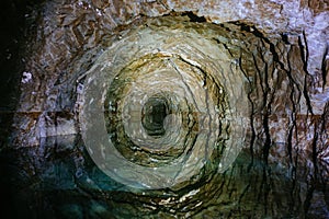 Dark flooded abandoned mine tunnel with water reflections