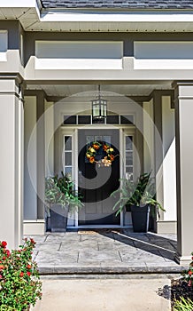 A dark fornt door and porch of a new construction house