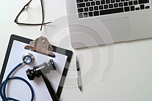 Dark Gavel With Medical Stethoscope near Laptop on white desk In