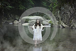Dark girl with a sword in a mountain stream