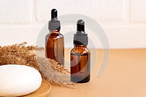 Dark glass bottles with essentia oils and face soap bar on beige background. Skin care concet with copy soace. Natural cosmetics