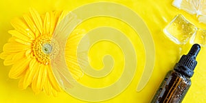 Dark glass essential oil, vitamin C serum on yellow background
