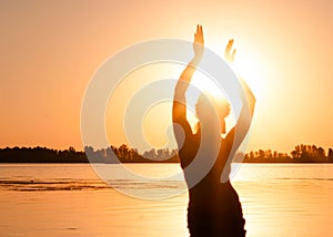 Silhouette of slim woman dancing traditional tribal belly dance on beach at sunrise