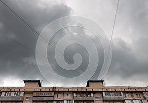 Dark gray clouds in the sky above a tall building bottom view with copy space