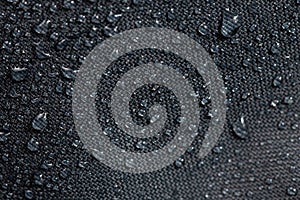 Dark gray waterproof hydrophobic cloth closeup with water drops selective focus background