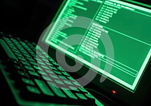 Dark Green Computer Screen Displaying Code with Keyboard in Low Light