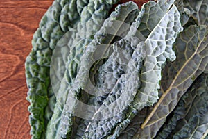 Dark green, crinkly, Lacinato Kale leaves on a wood table, part of healthy lifestyle