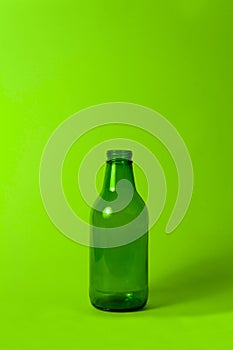 Dark green glass bottle on green background.