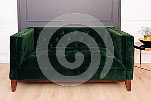 Dark green malachite velor sofa in the interior. Capitone textile, suede, velour, with buttons