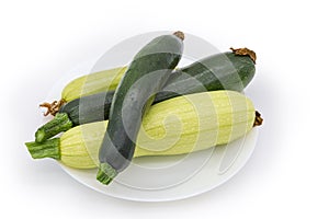 Dark green zucchini and light green marrows on white dish