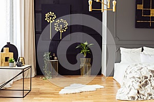 Dark grey bedroom interior with fur rug, gold accessories, simple painting and window with curtains in the real photo